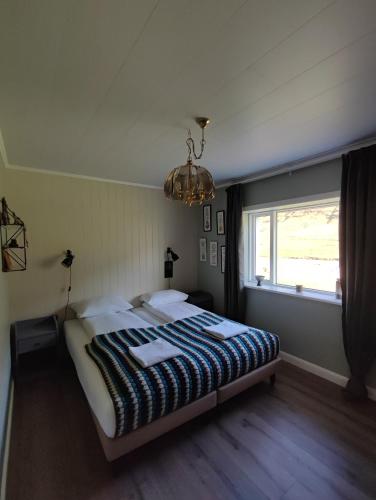 a bedroom with a bed and a window and a chandelier at Hóll in Óbyggðasetur