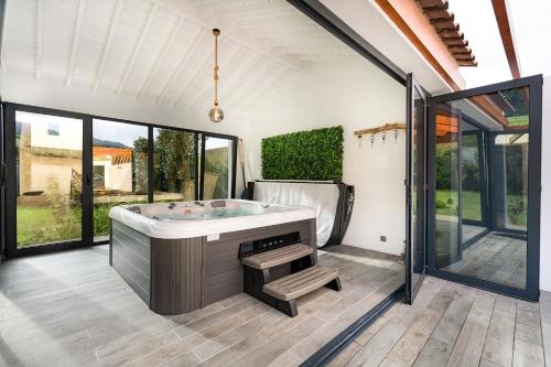 een grote badkamer met een bad en grote ramen bij WelcomeBuddy - São Brás Collection Jacuzzi&Garden in Porto Formoso