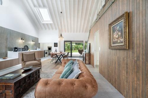 a living room with a brown couch and a kitchen at São Brás Luxury Home - Jacuzzi & Garden in Sao Bras
