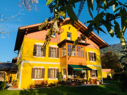 a yellow house with a wooden roof at Ferienwohnung Sonnwendhof "Kellerjochblick" in Schwaz