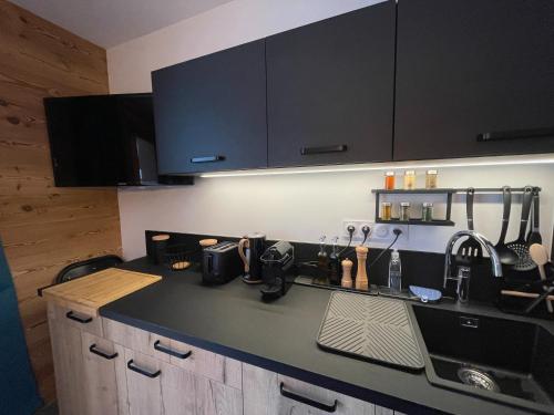 a kitchen with a black counter top and black cabinets at Le Roc in Saint-Jean-d'Aulps