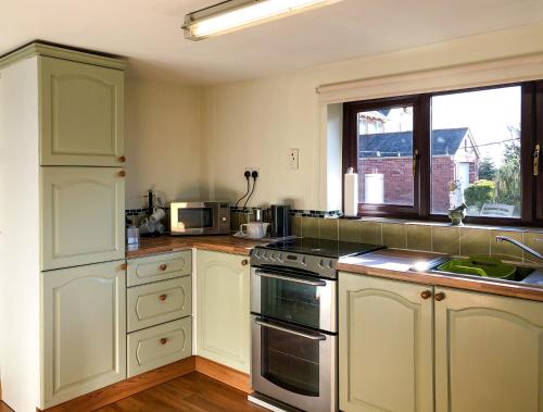 a kitchen with white cabinets and a stove top oven at Our Snug in Riccall