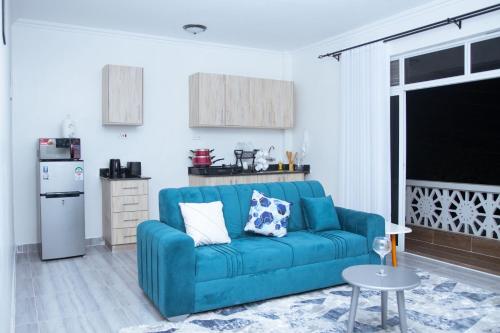 a living room with a blue couch and a kitchen at Kezmo Siloam Paradise in Mombasa
