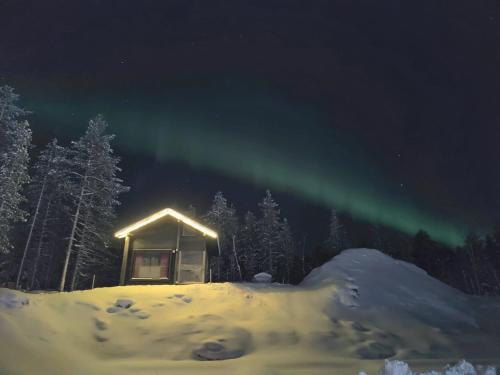 a cabin under the aurora in the snow at night at Lapland Aurora cabin in Rovaniemi