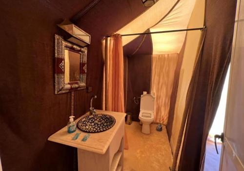 a small bathroom with a sink and a toilet at Merzouga best camp in Merzouga