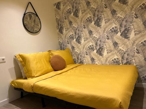 a yellow couch in a room with a clock on the wall at Lovely tiny house in Zandvoort