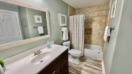 een badkamer met een wastafel, een toilet en een spiegel bij Tropic Winds 904 in Panama City Beach