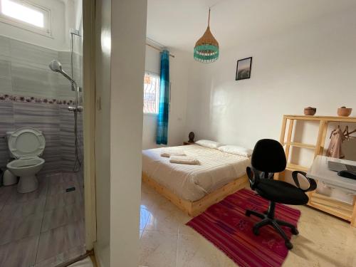 a bedroom with a bed and a chair and a shower at Cozy Surf House in Taghazout