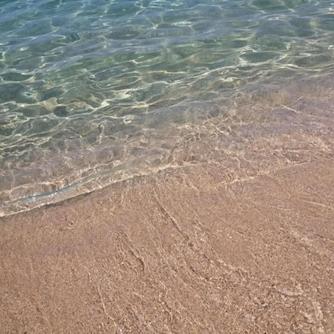 a close up of the sand and water at the beach at Casa vacanze con terrazza panoramica vista mare in Portu Maga