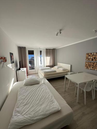 Habitación blanca con 2 camas y mesa en Apartments Kaninska Vas, en Bovec