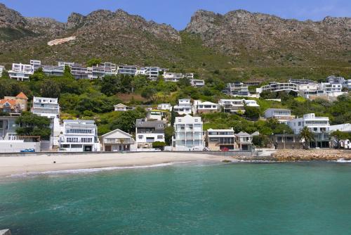 a group of houses on a beach next to the water at Gordonia 10 by HostAgents in Gordonʼs Bay