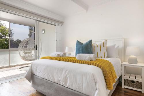 a white bedroom with a large bed with a yellow blanket at Gordonia 10 by HostAgents in Gordonʼs Bay