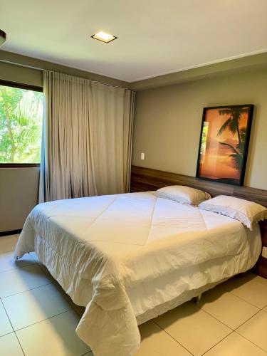 a bedroom with a large white bed with a window at Apartamento em Barra Bali, Resort de Luxo, Barra de São de Miguel - 223 in Barra de São Miguel