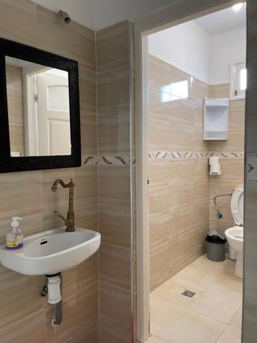 a bathroom with a sink and a mirror and a toilet at Cozy Surf House in Taghazout