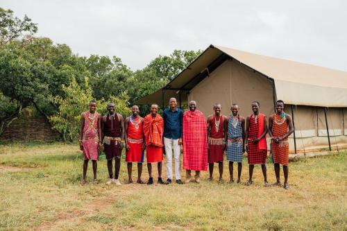grupa mężczyzn stojących przed namiotem w obiekcie Olimba Mara Camp w mieście Mara Simba