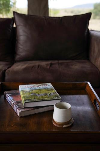 a coffee table with a book and a cup on it at Olimba Mara Camp in Mara Simba