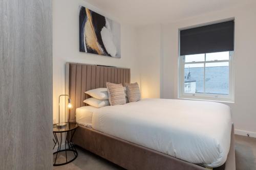 sypialnia z białym łóżkiem i oknem w obiekcie Deluxe North Central London Apartment w Londynie