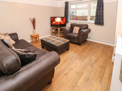 a living room with two couches and a tv at Sŵn Y Môr in Burry Port