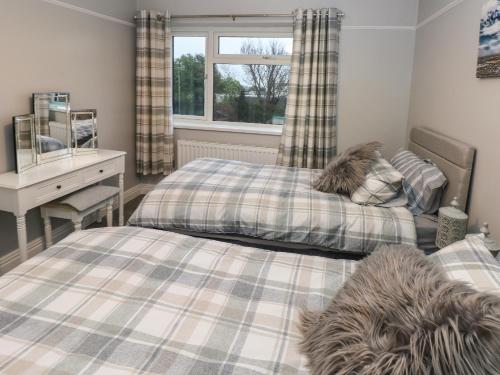 a bedroom with two beds and a desk and a window at Sŵn Y Môr in Burry Port