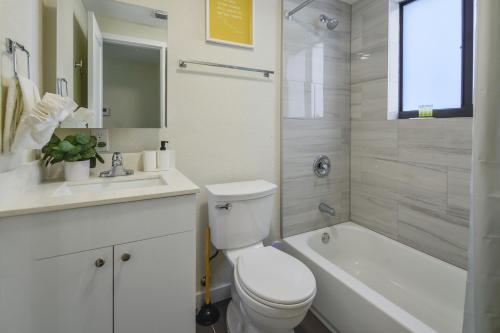 a bathroom with a toilet and a tub and a sink at Heart of Little Havana Awaits in Miami