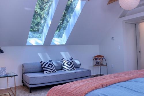a bedroom with a blue couch and two windows at Charming Scandinavian Modern Riverfront Fishhouse in Hailey