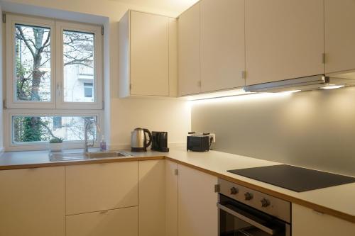 a kitchen with white cabinets and a sink and a window at Appartement House Jena in Jena