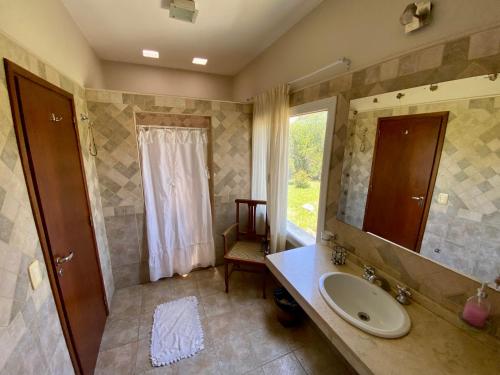 a bathroom with a sink and a mirror and a window at Posada Sausalito in Santa Rosa de Calamuchita