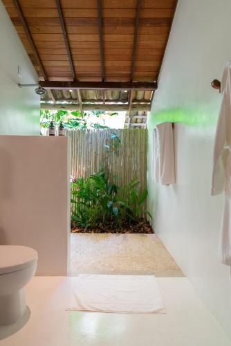 a bathroom with a toilet and a plant at Hotel Vila São João in Trancoso