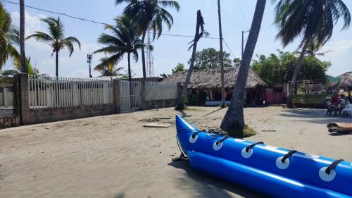 a blue boat sitting on the sand next to a tree at Cabaña 8 Arrecifes in Coveñas