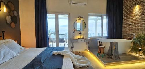 a bedroom with a bath tub and a large window at Aquamarine Villa in Agní