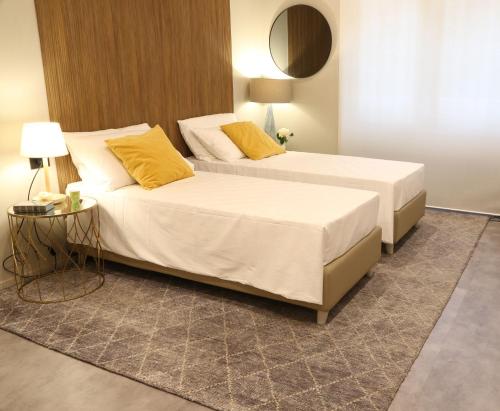 two beds with yellow pillows in a bedroom at Meyland suites centro in Milan