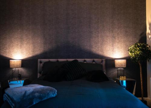 a bedroom with a blue bed with two lamps at THE MIRAGE in Market Rasen