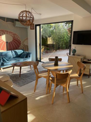 un salon avec une table, des chaises et un canapé dans l'établissement Charmant rez de jardin de villa, à Hyères