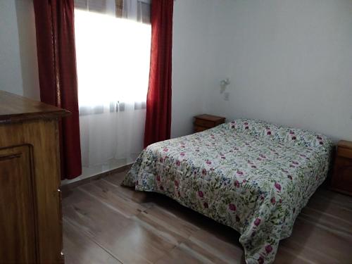 1 dormitorio con 1 cama con colcha de flores y ventana en Manto de Estrellas en San Rafael