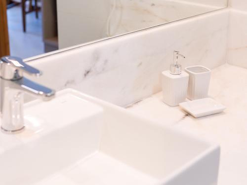 a white bathroom with a sink and a toilet at Hotel Velas do Engenho in Ilhabela