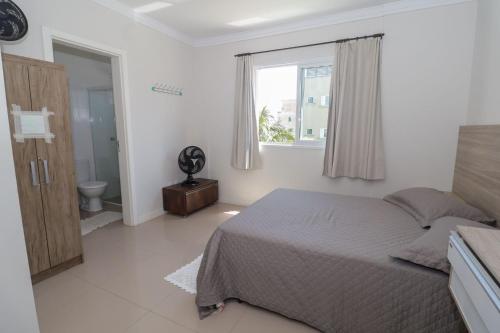 a bedroom with a bed and a window and a toilet at 377 - Belissimo apartamento na praia de Bombas in Bombinhas