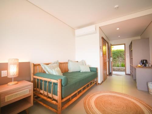 a living room with a green couch and a table at Hotel Velas do Engenho in Ilhabela