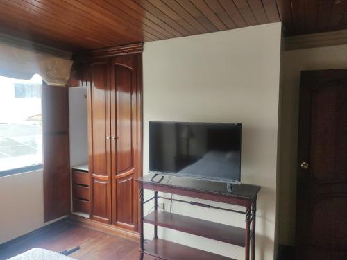 a living room with a flat screen tv and a table at Hotel Jardines del Rio in Loja