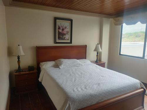 a bedroom with a bed and two lamps and a window at Hotel Jardines del Rio in Loja