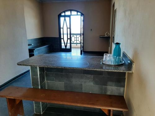 a kitchen with a counter and a bench in a room at Hospedagem Familiar in Piúma