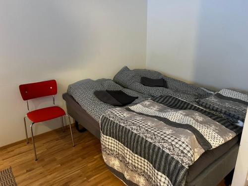 een slaapkamer met 2 bedden en een rode stoel bij AaltoStudio Alajärvi-Center in Alajärvi