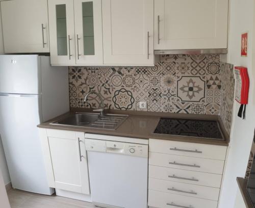 cocina con armarios blancos y nevera blanca en Tróia Beach Apartment, en Carvalhal