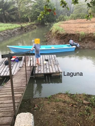 a young boy standing on a dock next to a boat at hotelsonidosamados-osa in Sierpe