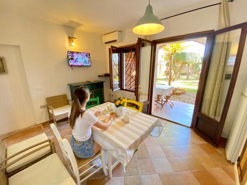 a woman sitting at a table in a room at Residence La Rosa in Porto San Paolo