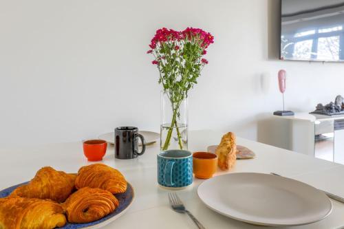 une table avec une assiette de pain et un vase avec des fleurs dans l'établissement Appartement Rodina - Welkeys, à Issy-les-Moulineaux