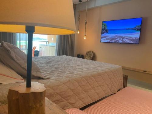 a bedroom with a bed and a tv on the wall at Beira-Mar EcoResort Carneiros perto da Igrejinha in Tamandaré