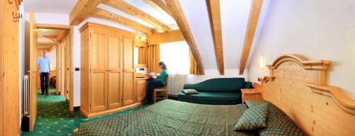 a room with a bed and a woman sitting in a room at Sporting Hotel in Passo del Tonale