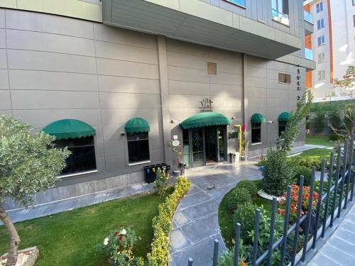 una vista exterior de un edificio con toldos verdes en YOUR HOUSE Apart Otel, en Karaköprü Köyü