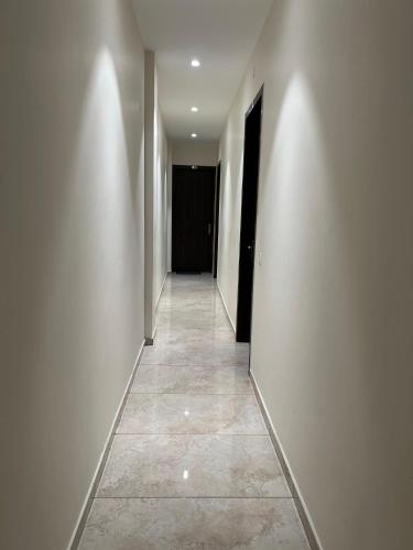 a hallway with white walls and a tile floor at HOTEL ANANTA in Ambāla