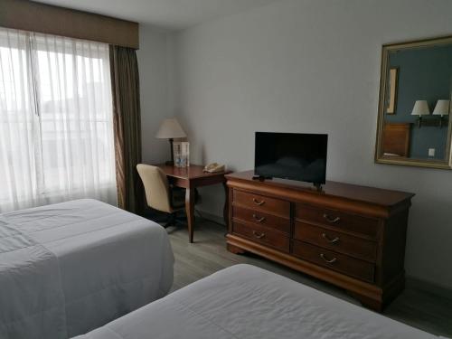Habitación de hotel con cama y tocador con TV en Sierra Huasteca Inn en Ciudad Valles